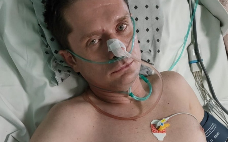 Mężczyzna leżący w szpitalnym łóżku, z tlenem i monitorami.
