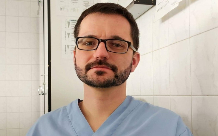 Mężczyzna w niebieskim fartuchu, patrzący w obiektyw.