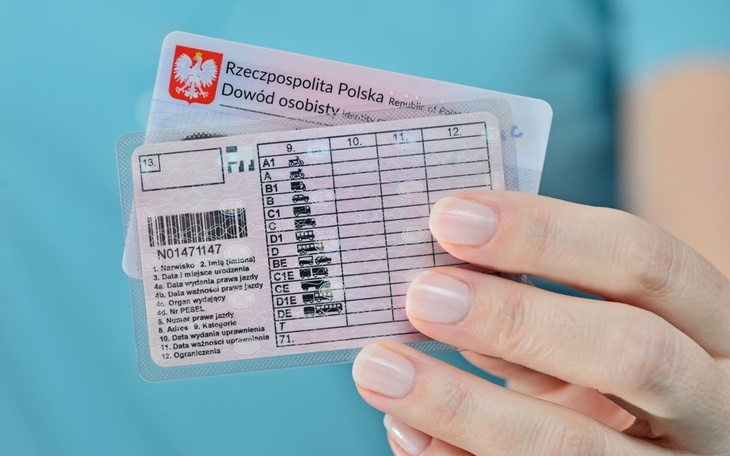 Osoba trzymająca dowód osobisty w dłoni.