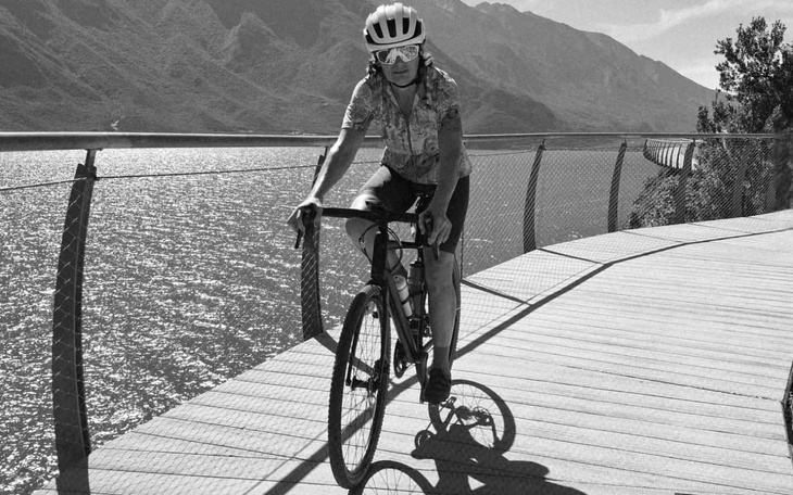 Kolarz na rowerze, jadący wzdłuż jeziora w górach.