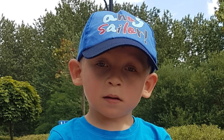 Chłopiec w niebieskiej czapce, patrzący w obiektyw.