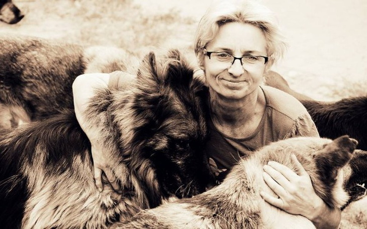 Kobieta przytulająca psy, w ciepłej, emocjonalnej chwili.