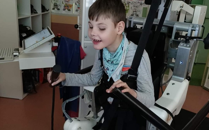 Chłopiec w urządzeniu wspomagającym, śpiewający z radością.