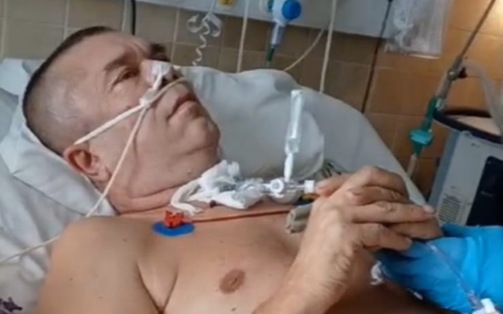 Mężczyzna w szpitalu, trzymający rurkę do podawania płynów.