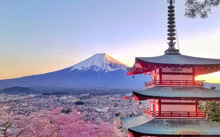Widok na g贸r臋 Fuji z pagod膮 i kwitn膮cymi drzewami.
