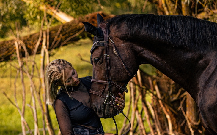 Kobieta przytulająca konia w naturalnym otoczeniu.