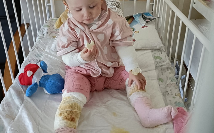 Małe dziecko siedzące w łóżeczku, bawiące się zabawką.