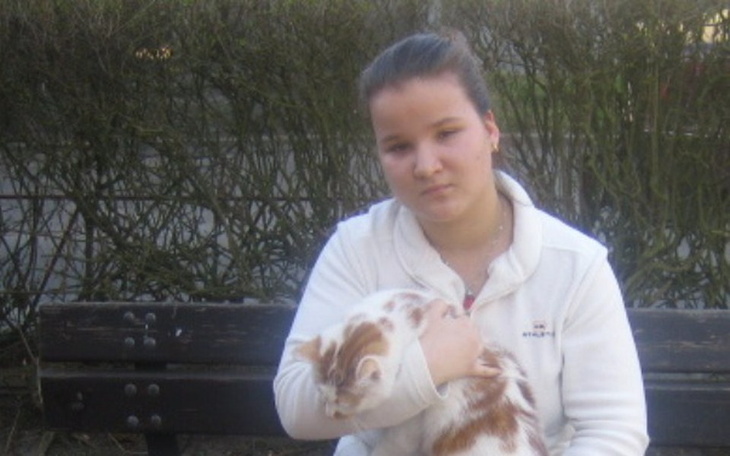 Dziewczyna trzymająca kota na ławce w parku.