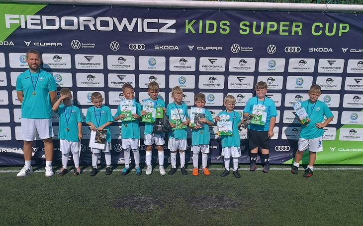 Dzieci z medalami na boisku piłkarskim.