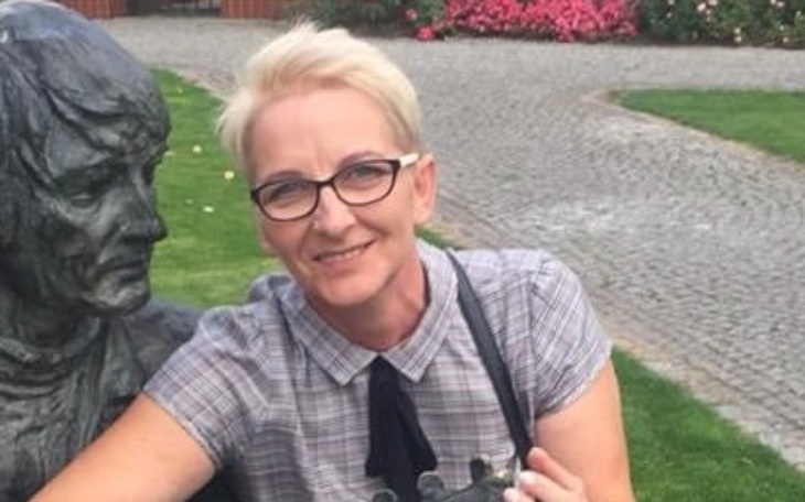 Kobieta pozująca przy pomniku, uśmiechnięta.