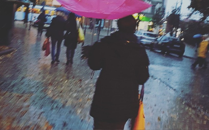 Osoba z parasolem spacerująca w deszczowy dzień.