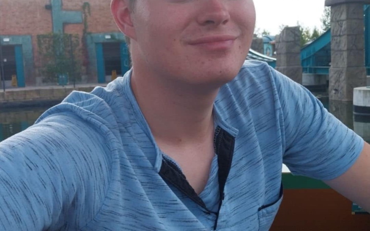 Młody mężczyzna uśmiecha się do kamery.