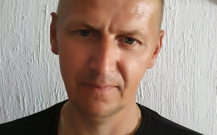 Mężczyzna z poważnym wyrazem twarzy, patrzący w obiektyw.