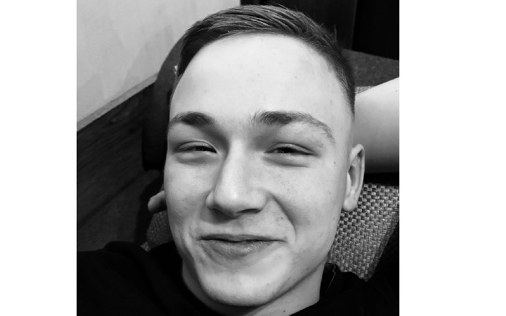 Młody mężczyzna z uśmiechem, leżący na kanapie.