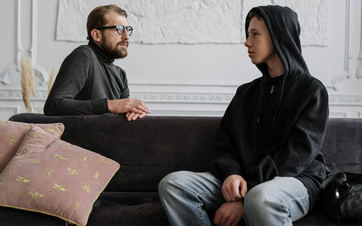 Dwie osoby rozmawiające na kanapie w eleganckim wnętrzu.