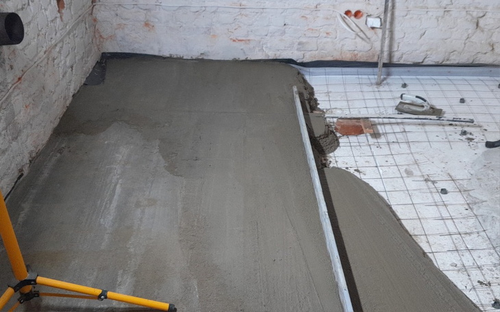 Nowo wylana posadzka w pomieszczeniu, przygotowana do dalszych prac.