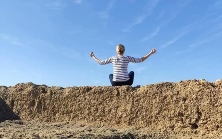 Osoba medytująca na plaży, siedząca na piasku.
