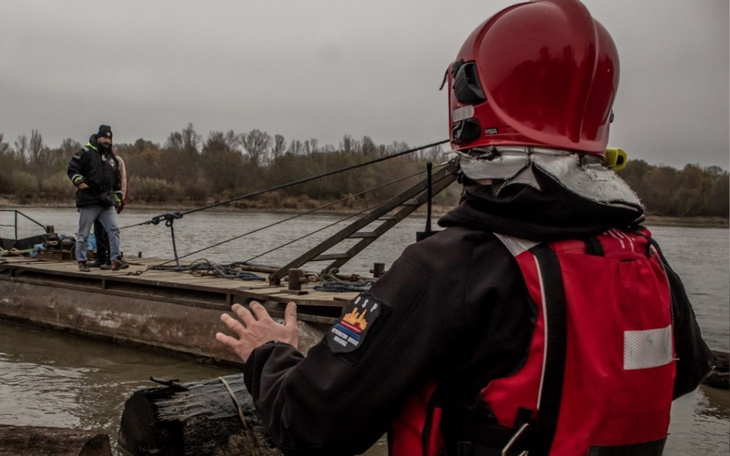 Ratownik wodny obserwujący akcję na rzece, w tle inny ratownik.