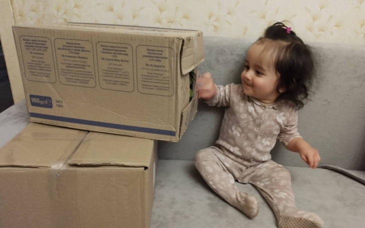 Mała dziewczynka bawi się przy kartonach na kanapie.