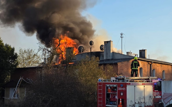 Pożar budynku, dym i ogień widoczne z daleka.