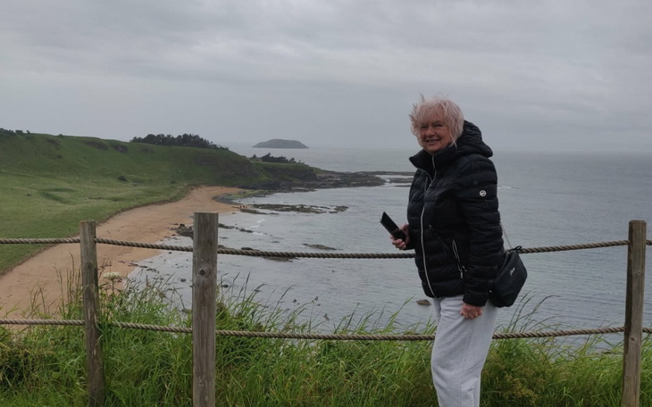 Kobieta na tle morza, uśmiechnięta, w casualowym stroju.