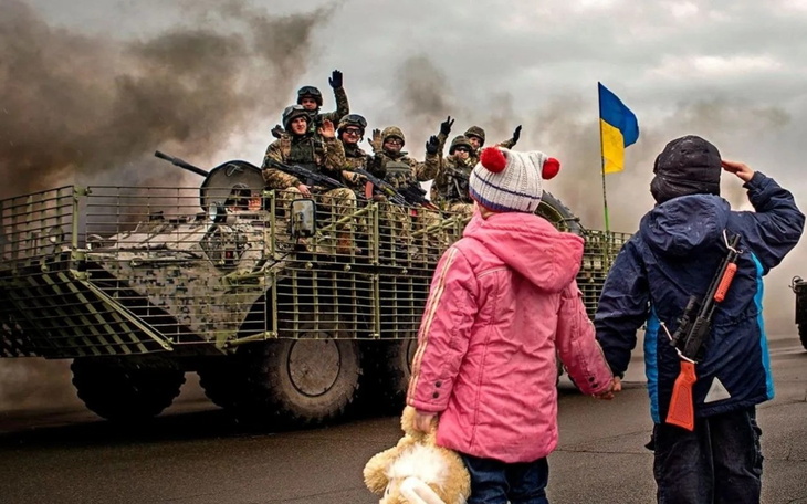 Dzieci machające do żołnierzy na opancerzonym pojeździe.