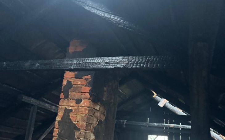 Zniszczony strop w budynku, czarne belki i cegły.