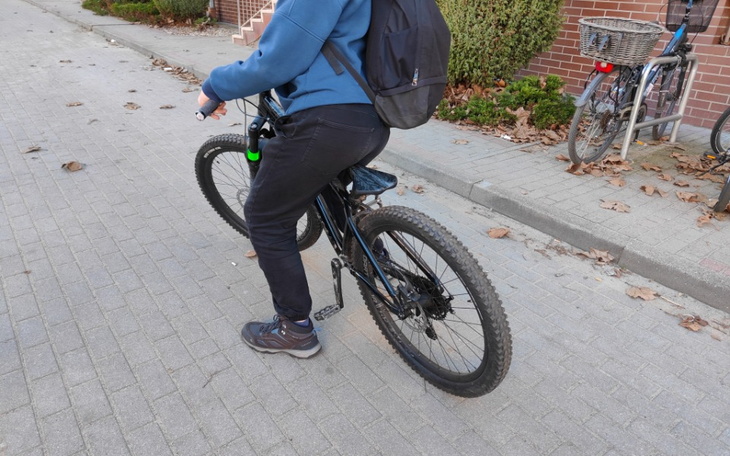 Osoba na rowerze, jadąca po brukowanej ulicy.