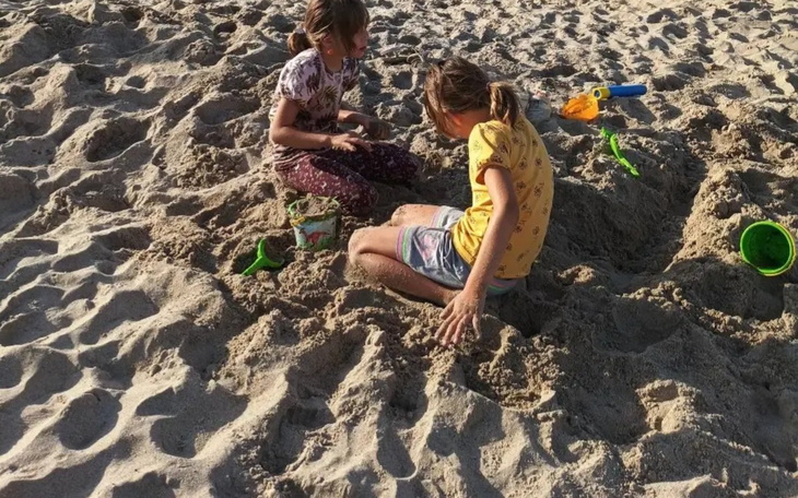 Dzieci bawią się w piasku na plaży z zabawkami.