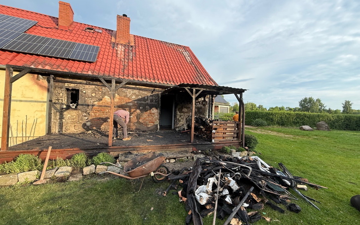 Zniszczony dom po pożarze, z osobą sprzątającą.