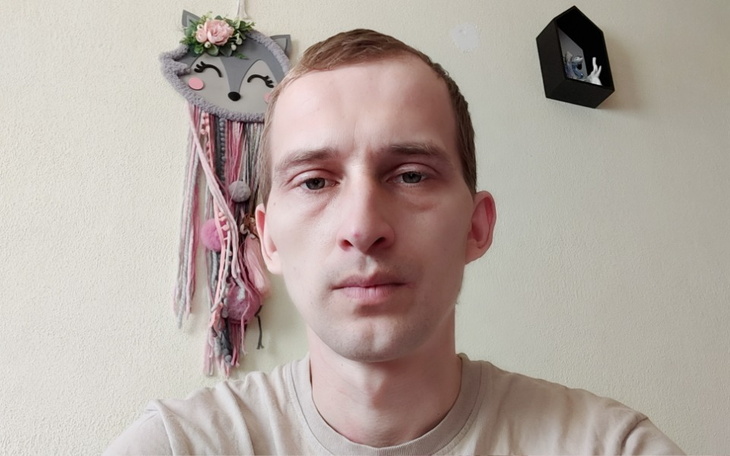 Mężczyzna z poważnym wyrazem twarzy, w tle dekoracje.