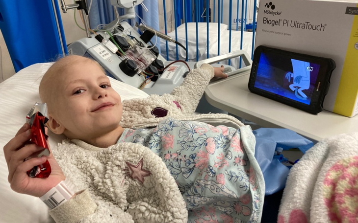 Chora dziewczynka w szpitalu, uśmiechająca się do kamery.
