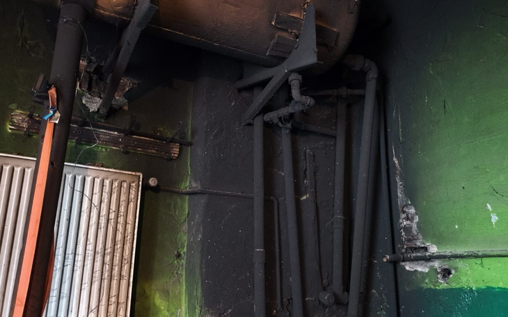 Ciemny kąt z rurami i ścianą pomalowaną na zielono.