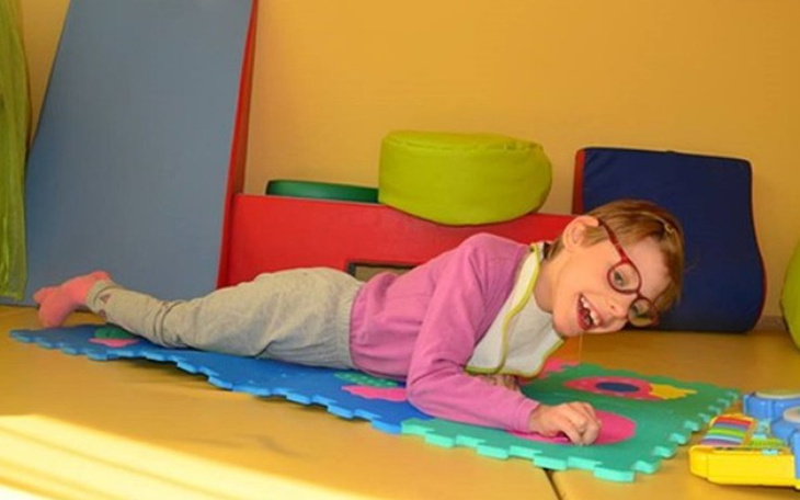 Dziecko leżące na macie, bawiące się zabawkami.