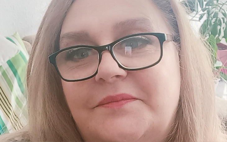 Kobieta w okularach, uśmiechająca się do kamery.