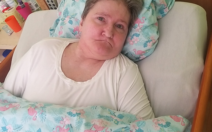 Kobieta leżąca w łóżku, przykryta kolorową pościelą.