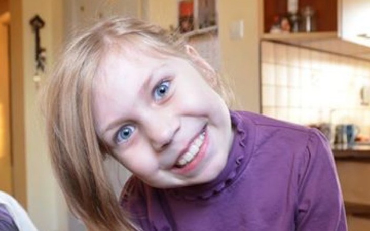 Uśmiechnięta dziewczynka z długimi włosami, pozująca do zdjęcia.