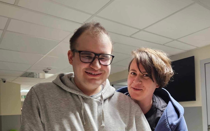 Młoda para uśmiechnięta, stojąca blisko siebie w szpitalu.