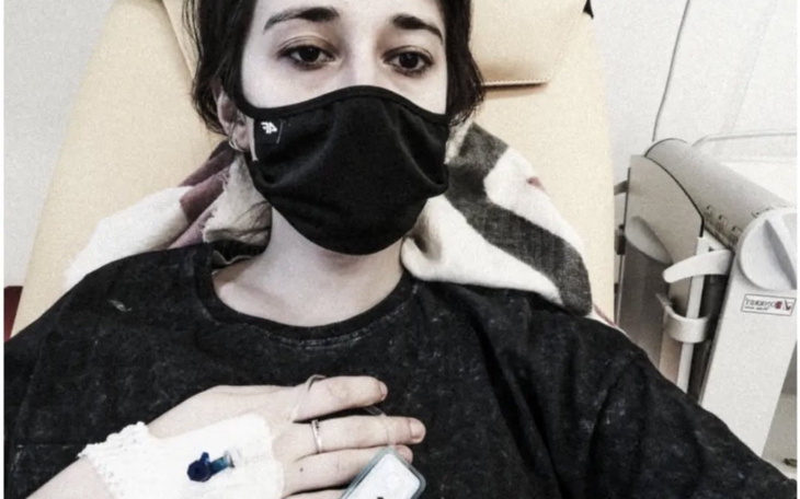 Młoda kobieta w maseczce, siedząca na fotelu w szpitalu.