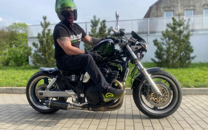 Mężczyzna na motocyklu, ubrany w czarną koszulkę.