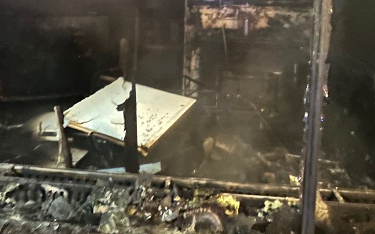Zniszczone wnętrze po pożarze, z popiołem i zgliszczami.