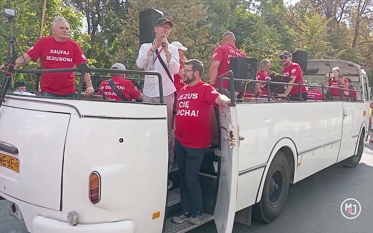 Grupa ludzi na platformie, z transparentami, podczas wydarzenia.