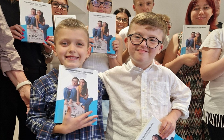 Dzieci trzymające książki, uśmiechające się do kamery.