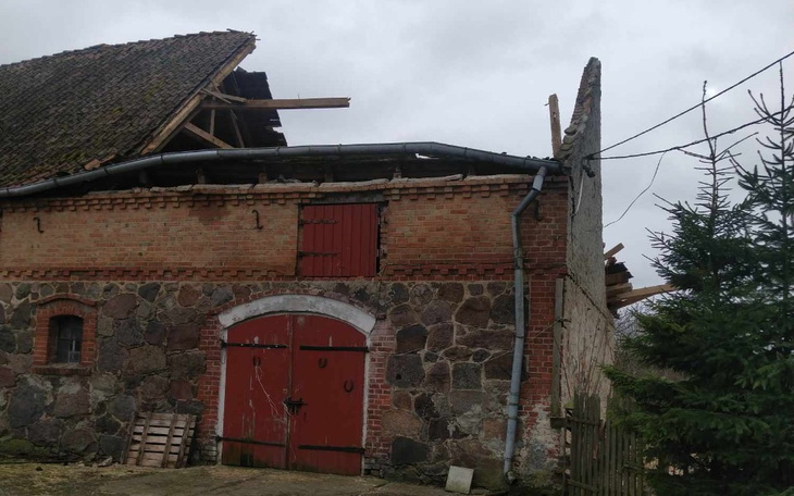 Zniszczony budynek gospodarczy z uszkodzonym dachem.
