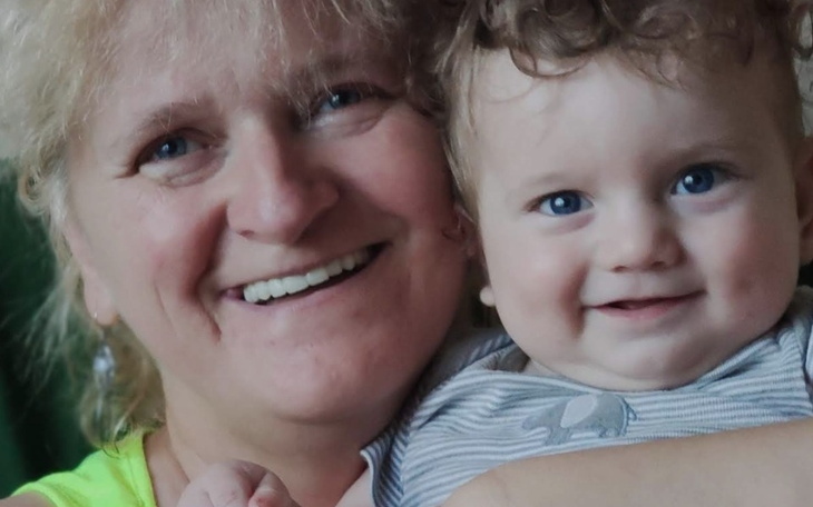 Uśmiechnięta kobieta z dzieckiem na rękach, pełna radości.