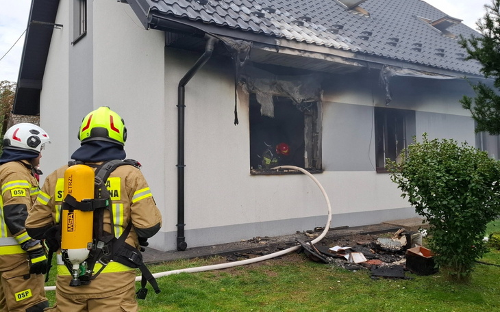 Strażacy przed uszkodzonym budynkiem, akcja gaśnicza na zewnątrz