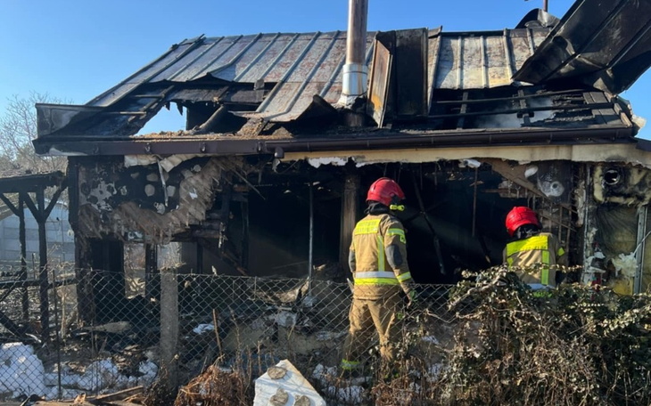 Strażacy przy zniszczonym budynku po pożarze.