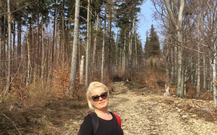 Kobieta w okularach przeciwsłonecznych na leśnej ścieżce.