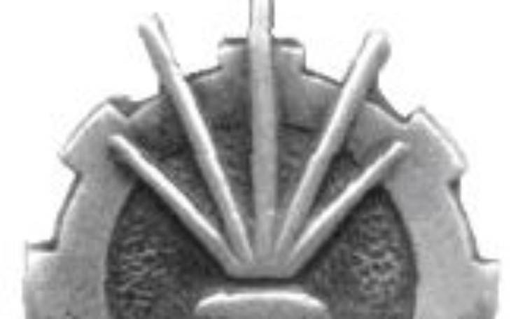 Stara odznaka z symbolem słońca i zębatki.