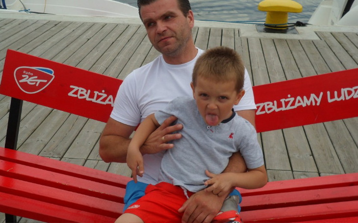 Mężczyzna z dzieckiem na ławce, robiący dziwną minę.